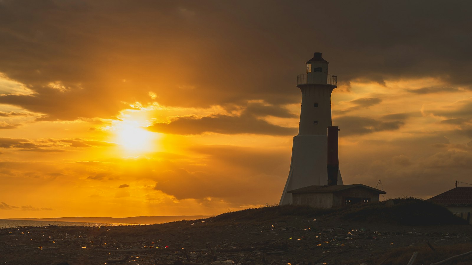 Lighthouse silhouetted against an orange sunset on the Kingston shoreline in Jamaica